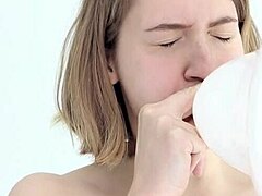 Young woman enjoys blowing and popping her first balloon with her mouth